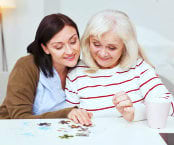 caregiver and senior woman playing puzzle